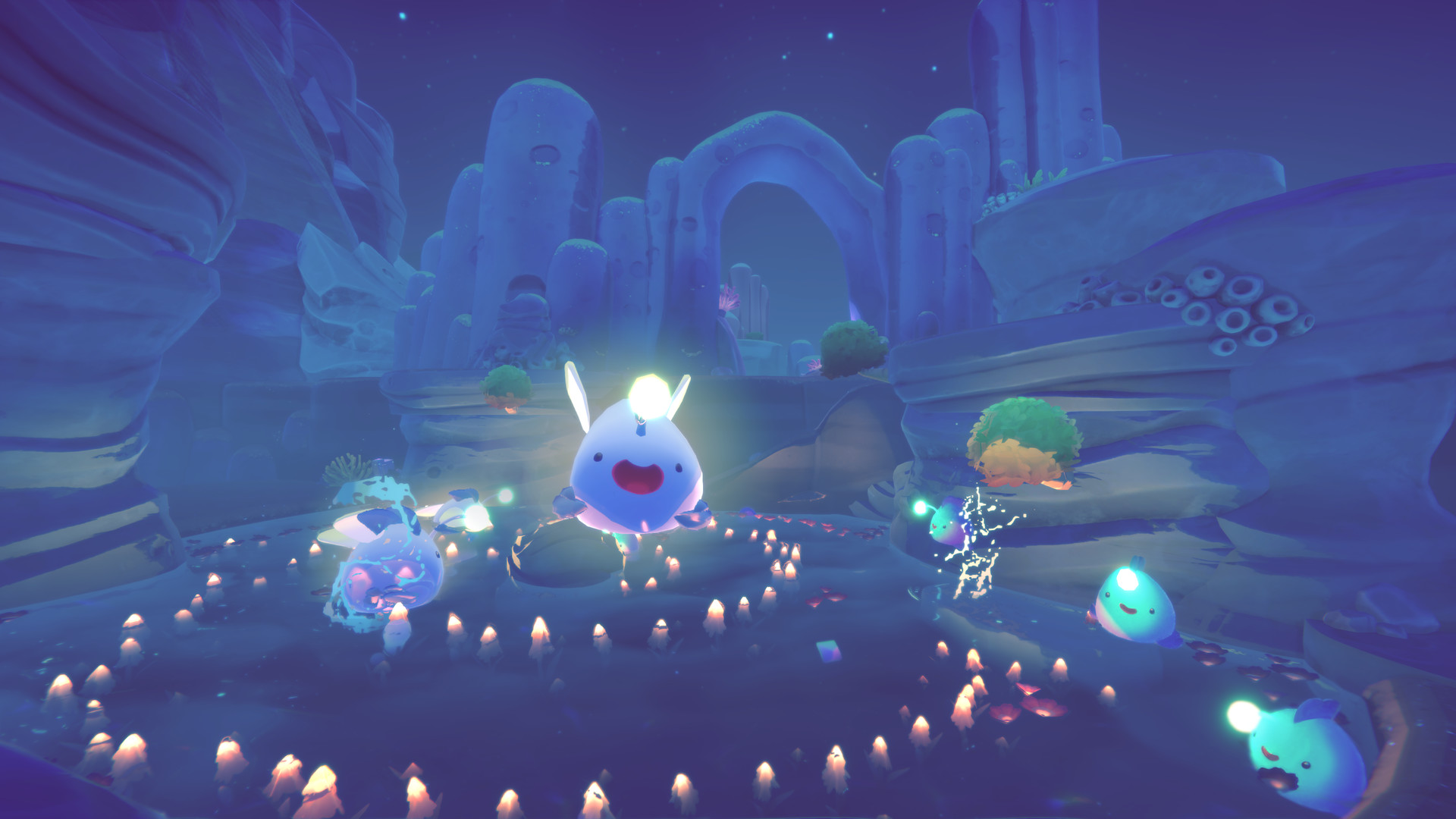 A screengrab from Slime Rancher 2 with glowing rocks and light blue slimes